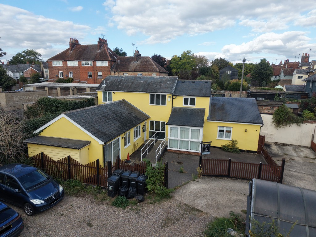 Lot: 6 - INVESTMENT OPPORTUNITY IN TOWN CENTRE LOCATION WITH OFF ROAD PARKING - Front aerial view of building with fenced parking